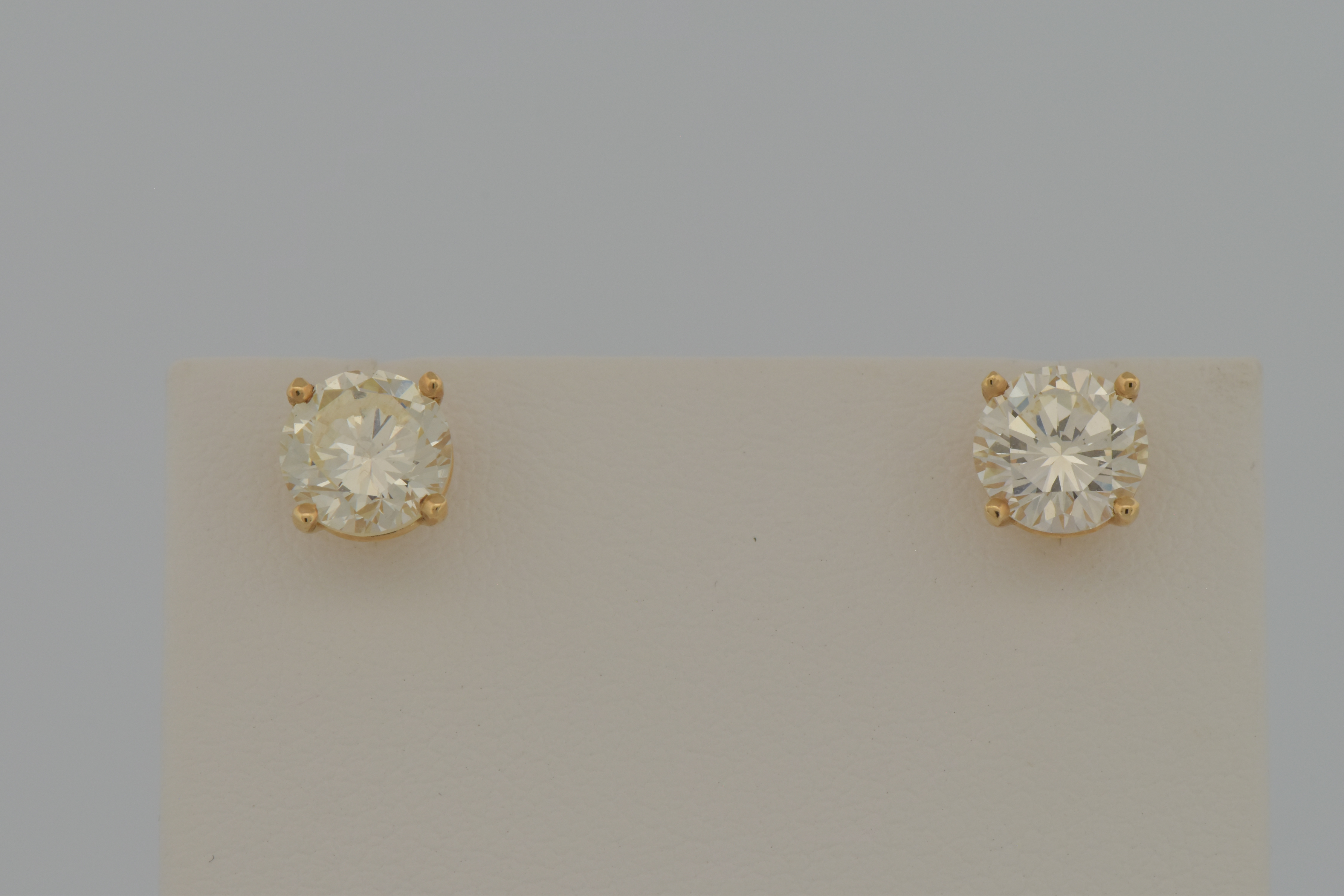 14K Yellow Gold Diamond Stud Earrings with a 1.01 Carat Round Cut Diamond, VS1 Clarity, M Color, GIA # 6224345966 and a 1.06 Carat Round Cut Diamond, VS2 Clarity, N Color, GIA # 2211727759.